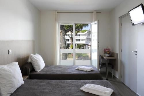 Habitación de hotel con 2 camas y ventana en Actif Residence, en La Grande-Motte