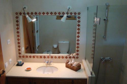 a bathroom with a sink and a shower with a mirror at Casa Da Oliveirinha in Casco