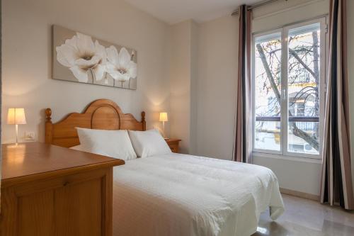 1 dormitorio con cama blanca y ventana en Apartamento cerca del Alcázar con garaje privado en Sevilla