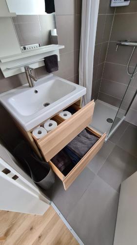 a bathroom with a sink and a shelf with towels at Top Floor Luxembourg City Studio with a Great View in Luxembourg