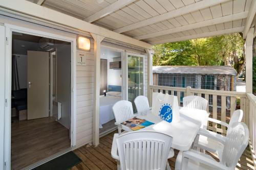 a porch with white chairs and a table and a bed at Club del Sole Adriano Family Collection in Punta Marina