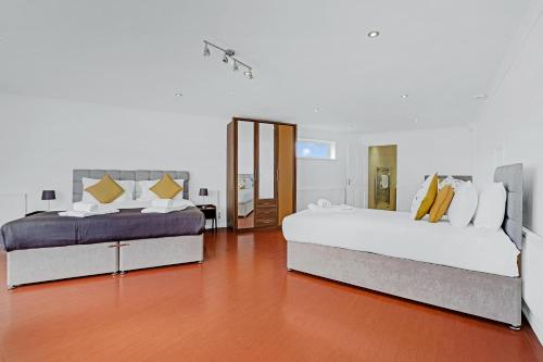 Habitación grande con 2 camas y suelo de madera. en Heathrow Living St Annes Serviced House 5 bedrooms 3 bath By 360Stays en Stanwell
