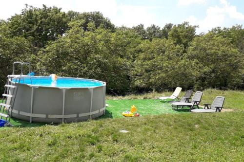 - un bain à remous dans l'herbe avec des chaises et une personne dans l'établissement Gîte st Julien des collines, à Le Grand Serre