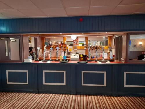 a bar with a blue counter with many glasses at The Avenue Club and Lodge in Birmingham