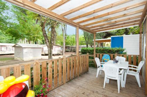 a wooden deck with a white table and chairs at Club del Sole Adriano Family Collection in Punta Marina