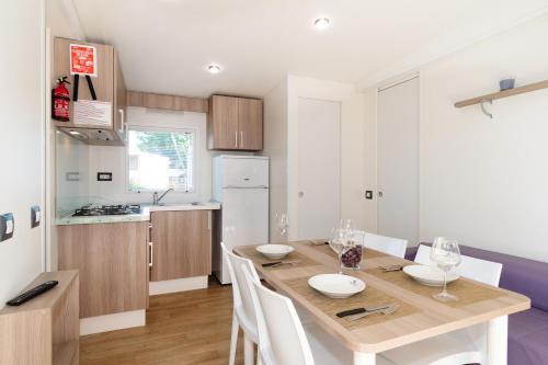a kitchen and dining room with a wooden table and chairs at Club del Sole Adriano Family Collection in Punta Marina