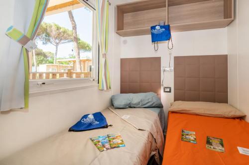 una piccola camera con due letti e una finestra di Adriano Family Camping Village a Punta Marina