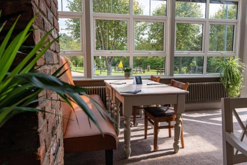 a table and chairs in a room with windows at Dragonfly Hotel Bury St Edmunds in Bury Saint Edmunds