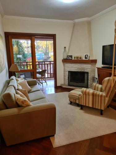 uma sala de estar com um sofá e uma lareira em Apartamentos Centrinho Capivari - Condomínio Recanto do Boticário em Campos do Jordão