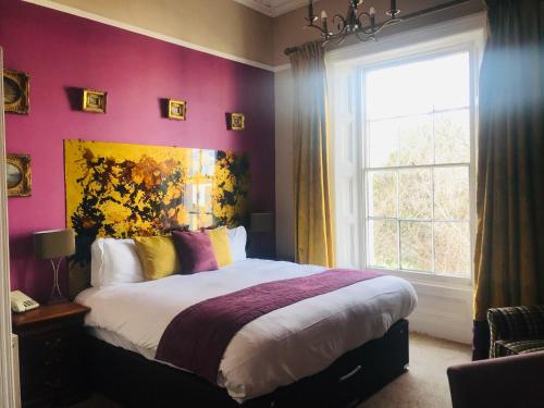 a bedroom with a large bed and a window at Clarence Court Hotel in Cheltenham