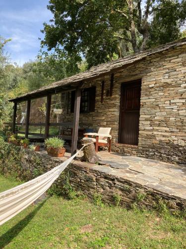 a stone house with a porch and a bench at Quinta da Recochina in Castro Daire