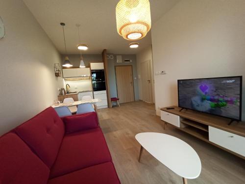 sala de estar con sofá rojo y TV de pantalla plana en Apartamenty Września, en Września