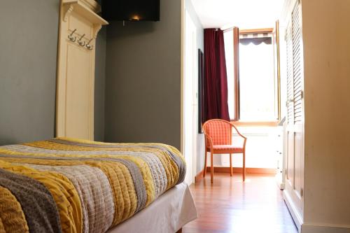 a bedroom with a bed and a chair and a window at Auberge de la Vieille Ferme in Le Meux