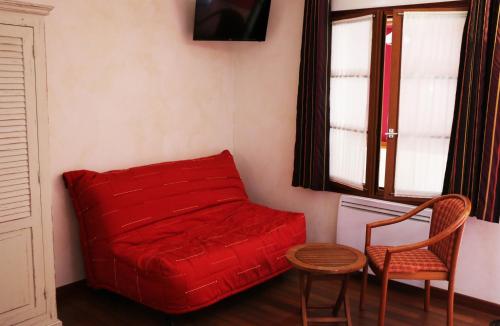 a red couch in a room with a table and a chair at Auberge de la Vieille Ferme in Le Meux