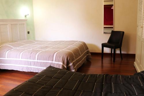 a bedroom with two beds and a black chair at Auberge de la Vieille Ferme in Le Meux