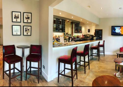 a bar with red chairs and a counter at Clarence Court Hotel in Cheltenham