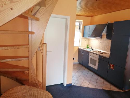 a kitchen with a staircase leading to a kitchen with blue cabinets at Gasthof-Ferienwohnungen-Kliesow´s Reuse in Alt Reddevitz