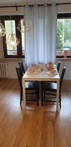 een eettafel met stoelen en een witte tafel met eten erop bij Corso Nobile Apartament in Płock