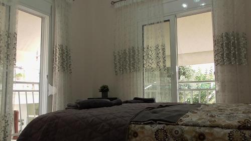 a bedroom with a bed and two large windows at Ellada Apartment in Athens