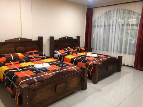 two twin beds in a room with a window at Hospedaje Adrimaran in Palmares
