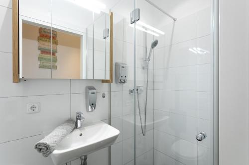 biała łazienka z umywalką i prysznicem w obiekcie Apartment, modern und neu renoviert w Wiedniu