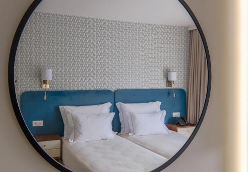 a bedroom with a bed with a blue headboard and white pillows at Hotel Vouga in Termas de Sao Pedro do Sul