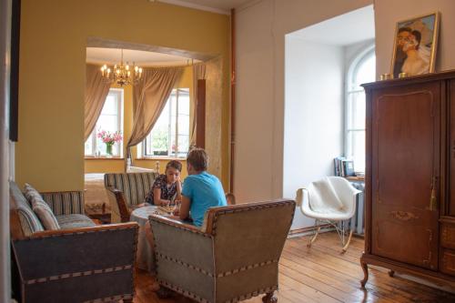 two people sitting at a table in a living room at Roberta Hercberga Apartamenti in Kuldīga