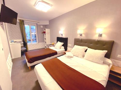 a hotel room with two beds and a television at Hotel Aviatic in Paris