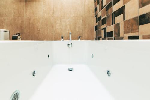 a bathroom with a white tub with two faucets at Blackwood Boutique Hotel and Apartments in Dar es Salaam