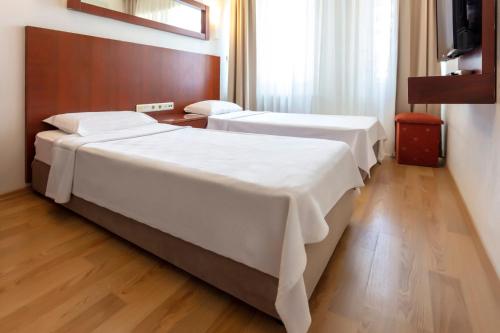 two beds in a hotel room with a television at Hotel Pelit in Canakkale