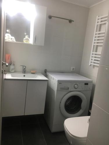 La salle de bains blanche est pourvue d'un lave-linge et d'un lavabo. dans l'établissement Home Sweet Home - 1 bedroom apartment, à Athènes