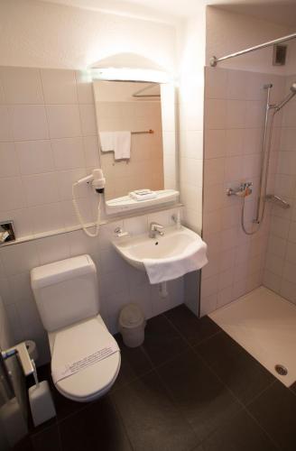 a bathroom with a toilet and a sink and a shower at Hotel Metropol in Widnau
