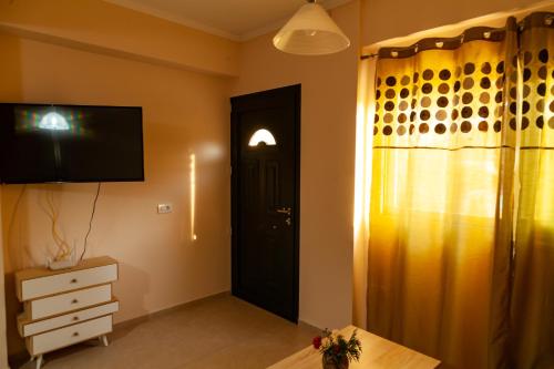 a room with a door and a dresser and a television at Tsoutsis Apartments in Marantochori