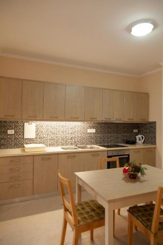 a kitchen with wooden cabinets and a table with chairs at Tsoutsis Apartments in Marantochori