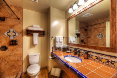 a bathroom with a toilet and a sink and a mirror at Hotel Mission De Oro in Santa Nella Village