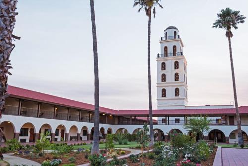 a building with a clock tower with palm trees at Hotel Mission De Oro in Santa Nella Village