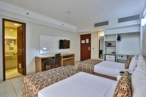 a hotel room with two beds and a desk at Quality Hotel & Suítes São Salvador in Salvador