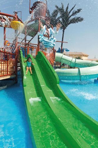 a child sliding down a water slide at a water park at Mövenpick Hotel Cairo - Media City in 6th Of October