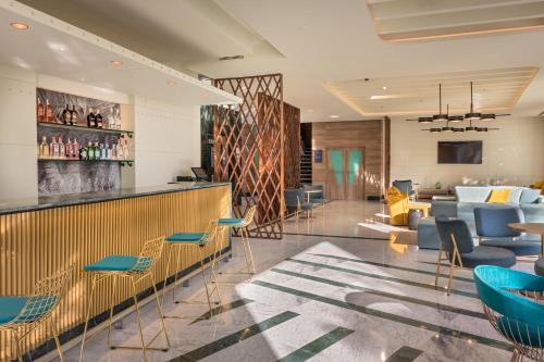 a bar in a hotel lobby with blue chairs at Occidental Sevilla Viapol in Seville
