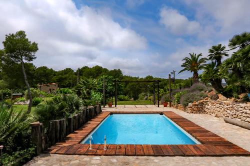 una piscina en un jardín con una valla de madera en Masia Pou de la Vinya, en Sitges