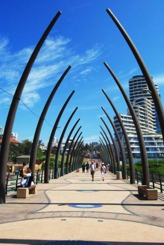 a group of people walking down a sidewalk with palm trees at Sancta Maria 10 - Ultimate in luxury & majestic sea views includes private entertainment deck - Free wifi in Kingsburgh
