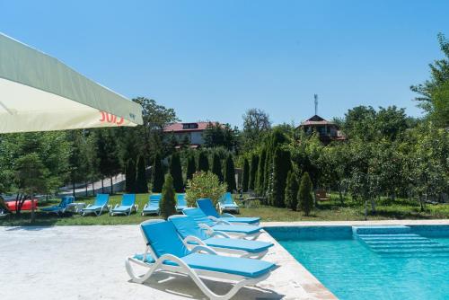 a row of blue lounge chairs next to a swimming pool at Pensiunea Știuca Șchioapă in Băltenii de Sus