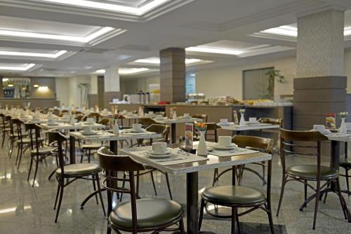 a row of tables and chairs in a restaurant at Astron Suítes São José dos Pinhais by Nobile in São José dos Pinhais