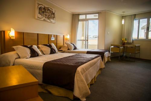 a hotel room with two beds and a couch at Barbur Plaza Hotel in Ponta Grossa