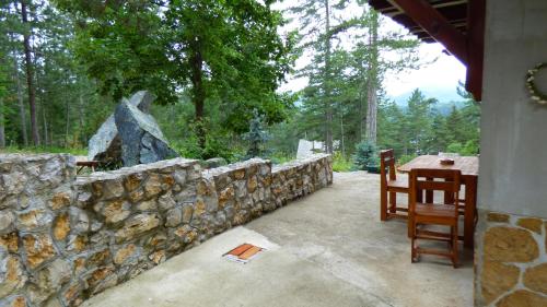 a stone retaining wall with a table and chairs on a patio at SVETLA U PLANINI in Bajina Bašta