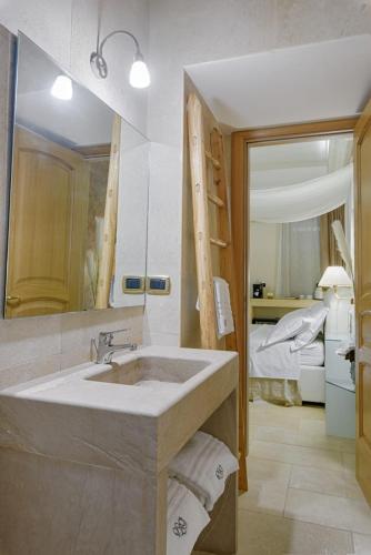 a bathroom with a sink and a bedroom with a bed at Egò Salento in Galatina