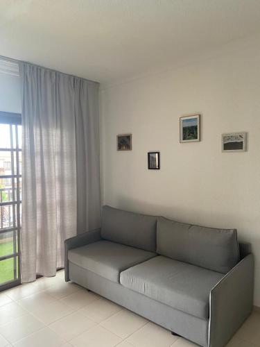un sofá en una sala de estar con ventana en Wait and Sea Apartment Costa del Silencio Tenerife en Arona