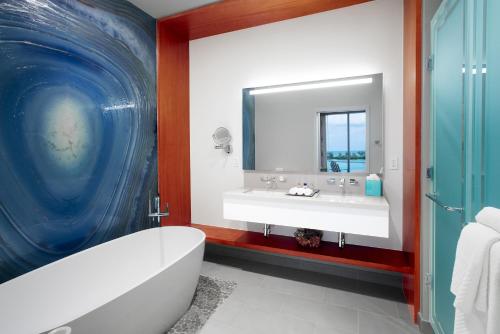 a bathroom with a tub and a sink and a mirror at Margaritaville Beach Resort Nassau in Nassau