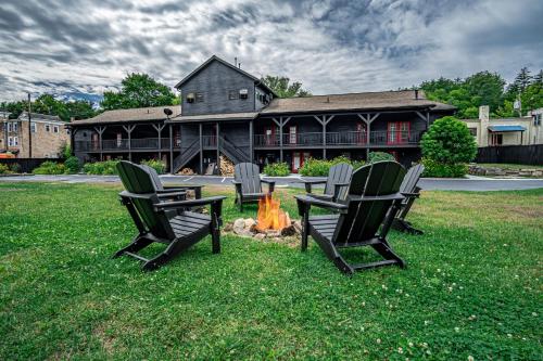 a group of chairs sitting around a fire in front of a house at The Alpine Lodge in North Creek