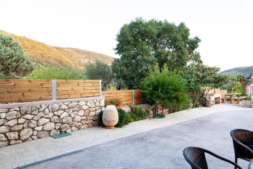 a fence with a stone wall and chairs on a patio at Tsoutsis Apartments in Marantochori